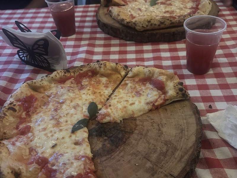Pizza de Grazia con un vaso de refresco natural sobre mantel a cuadros